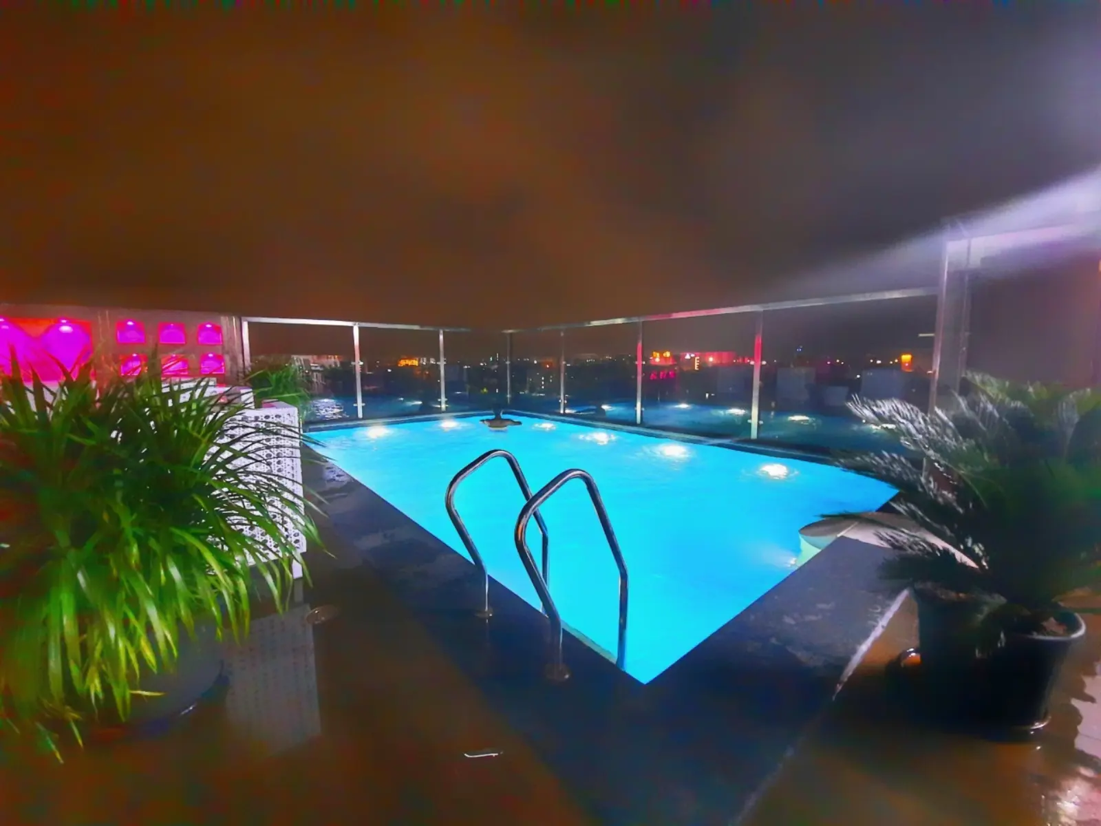Night-lit residential pool with glass railing by CreativPools